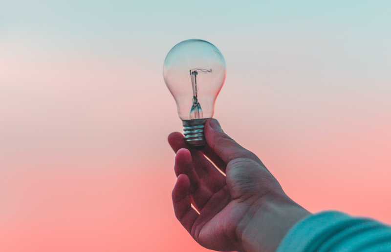 A hand holding a lightbulb that is not illuminated